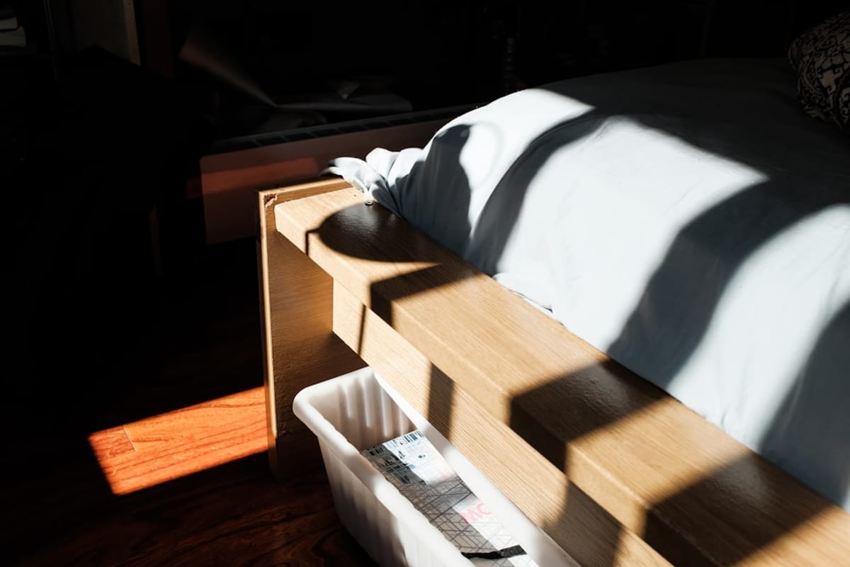 Use Multi-Functional Furniture and Smart Storage shadows on a bed with a wood frame